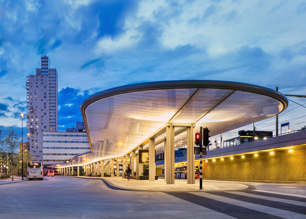 Het gerenoveerde busstation van Tilburg met zijn kenmerkende verlichte overkapping bij schemer. 