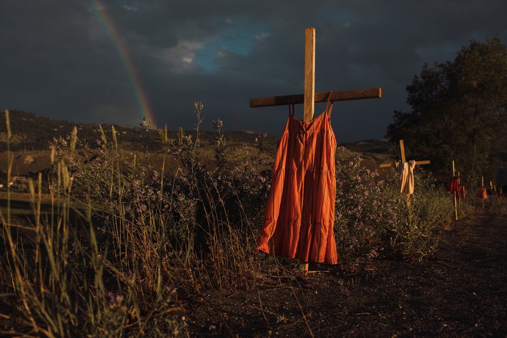 De winnende foto van Amber Bracken van de kruizen met kinderkledij en de regenboog